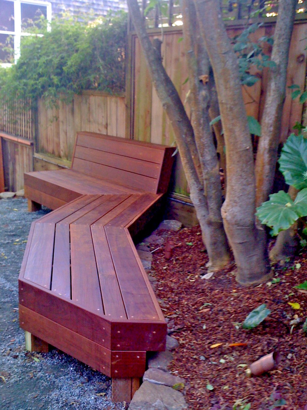 Redish stained 3 piece bench cut to angle around a tree