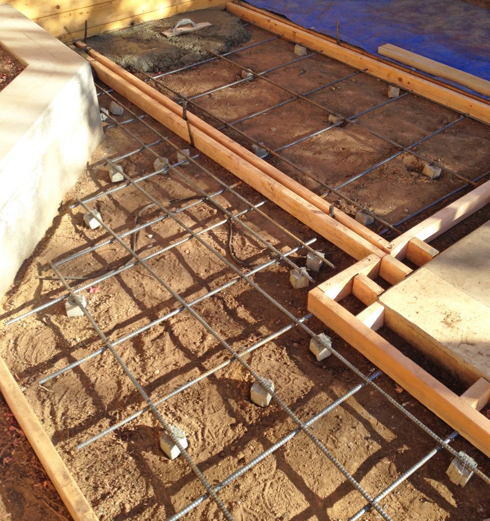 Close up of clean leveled dirt and rebar supports with wood framed sections in preparation for pouring cement