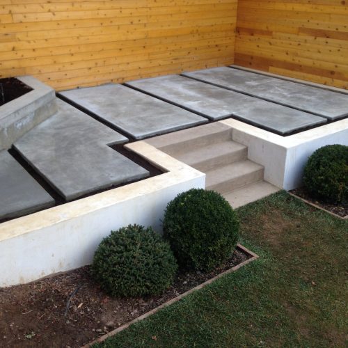 Five piece grey stained concrete slabs in elevated patio nook with matching angled planter