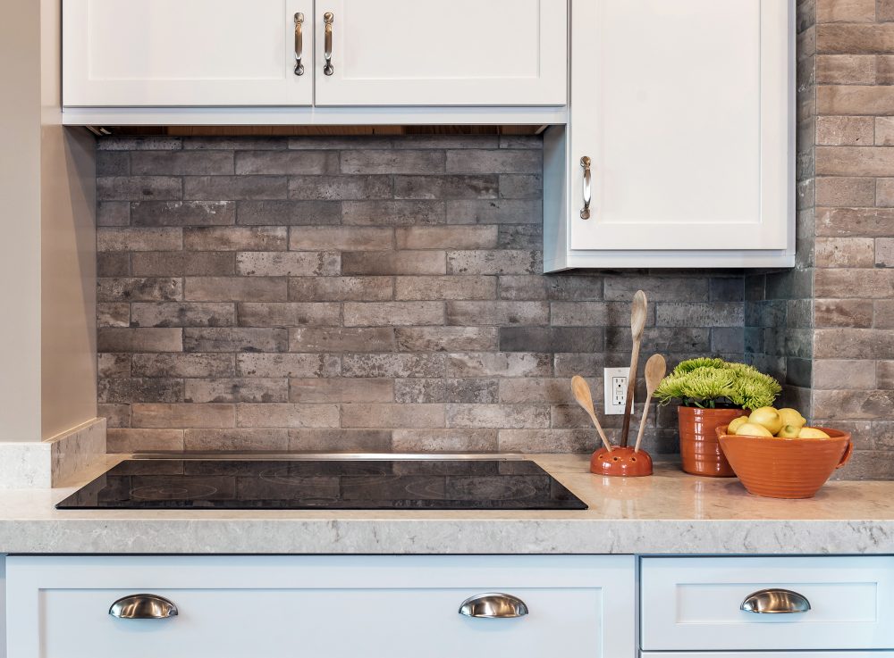 Modern black electric stovetop with counterspace on the right and white cabinets above