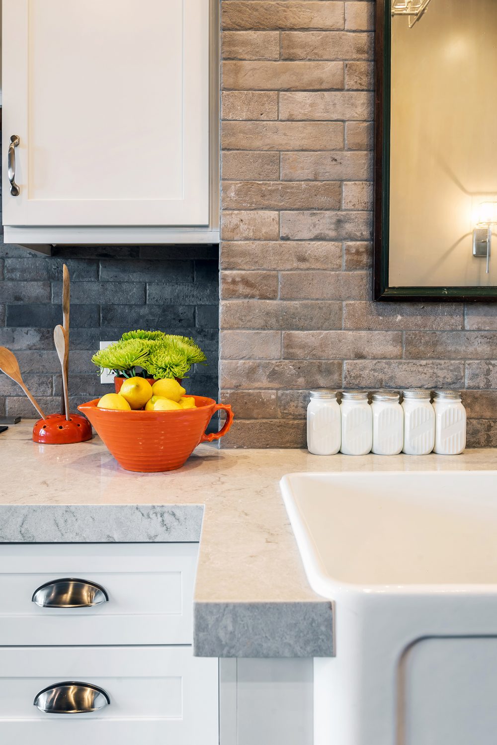 Close-up of white sink with marble counter and stone backsplash
