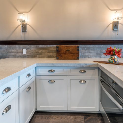 U-shaped white marble countertop with two rows of cabinets under counter and oven
