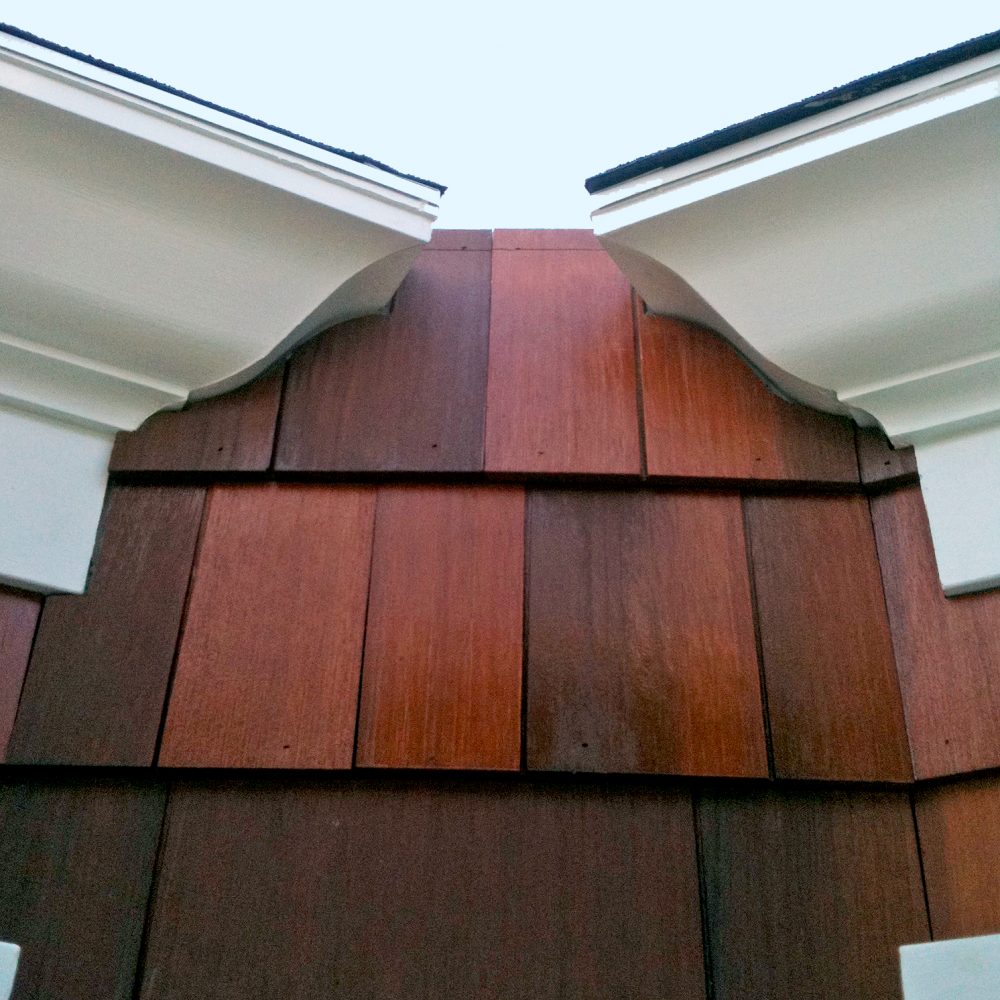 Large heavy duty white molding at the corner of a rooftop against large dark brown shingles