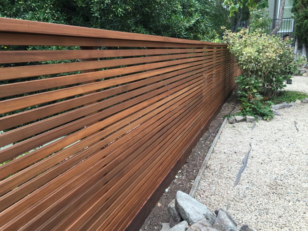 Long wooden slat fencing with space between the boards