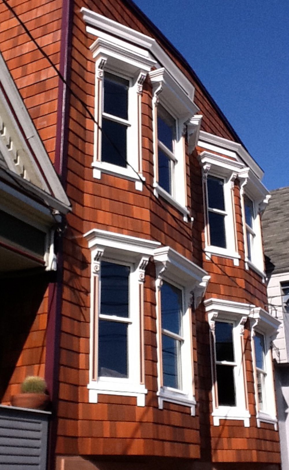 Exterior windows with beautiful detailed molding painted in white on a brown shingled house