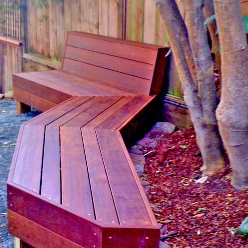Redish stained three piece bench cut to angle around a tree