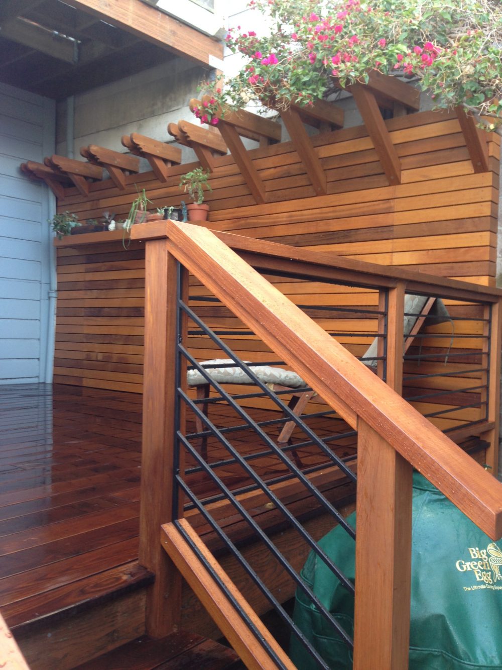 Wood patio with steps with cable railing; flower awning atop the fence